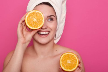 Hoş görünümlü genç Avrupalı kadın Stüdyo çekim turuncu halh ile göz kapakları ve elinde başka bir parçası tutarak, çekici kadın kafasına beyaz havlu vardır, net bir cilde sahiptir. Güzellik konsepti.