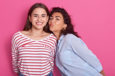 İki genç hipster kız yakın portresi, en iyi arkadaş, rahat gömlek giyen, büyük zaman togather sahip, dalgalı saç öpüşme jest yapma kadın, pembe arka plan üzerinde izole poz kadınlar.
