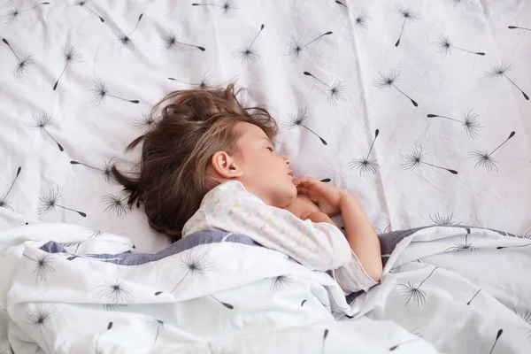 Little dark haired girl wearing white shirt sleeping in bed, lying — Stock Photo, Image