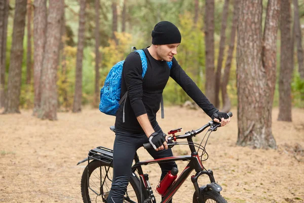 Na podzim nebo na jarním inspirující lesní krajině si na svém kole uzavřete portrét biker, pohledného mladého muže jezdoucího po silnici v lese. Koncepce sportu, aktivní rekreace a inspirace. — Stock fotografie