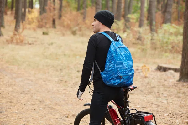 Horský biker na pěšině v lese, mladý muž na kole MTB na lesní cestě, pohledný muž s černým sportovním oblečením a čapkou v otevřeném vzduchu. Sportovně fitness motivace a koncepce inspirace. — Stock fotografie