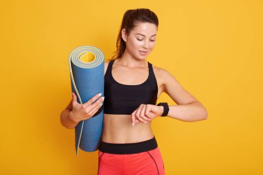 Stüdyo çekimlerinden sonra kadın antrenmanı sonuçları fitness uygulamasında kontrol eder, kadın akıllı saate bakar, beden eğitiminden sonra harcanan kalorileri sayar. Spor ve sağlıklı yaşam tarzı kavramı.
