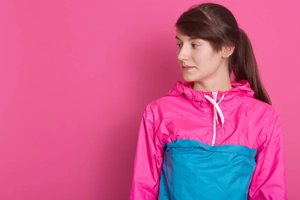 Portrait de jolie femme sportive en chemise sportive, charmante dame à la queue de cheval, regardant de côté, isolée sur fond de studio de pionk. Espace de copie pour votre texte publicitaire ou promotionnel . — Photo