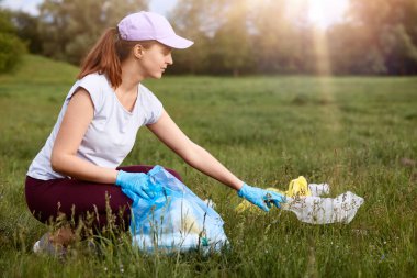 Genç çekici bir kadın çöpleri toplayıp yeşil çayırlara koyar. Çevresel gönüllü temizlik alanı ve güzel doğanın tadını çıkarır. Çevresel sorunları çözer..