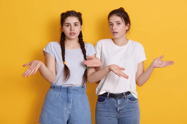 2人の若い十代の女の子が白いTシャツを着て手を広げ 無力ジェスチャーを示し 顔の表情を驚かせ 口を開けておきます — ストック写真