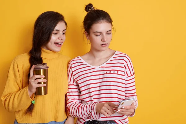 Két Barát Megosztása Intelligens Telefon Kávézás Együtt Pózol Elszigetelt Sárga — Stock Fotó