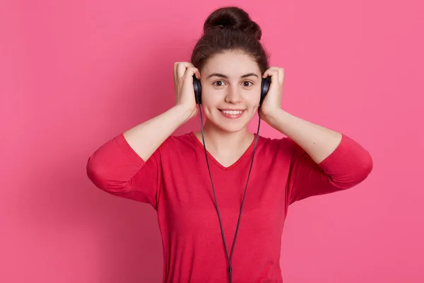 Nastolatka Uroczym Uśmiechem Stojąca Różowym Tle Słuchawkami Dotykając Zestawu Słuchawkowego — Zdjęcie stockowe