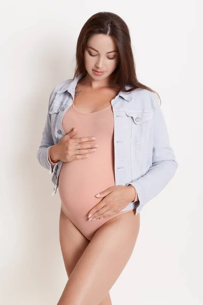 Milující Těhotné Ženy Při Pohledu Břicho Zatímco Pózuje Proti Bílé — Stock fotografie