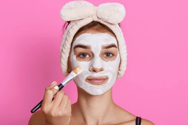 Atractiva Hembra Aplicando Mascarilla Facial Arcilla Cara Mirando Directamente Cámara — Foto de Stock