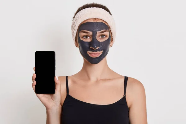 Piękna Uśmiechnięta Dziewczyna Czarną Maską Twarzy Trzymająca Smartfon Pustym Ekranem — Zdjęcie stockowe