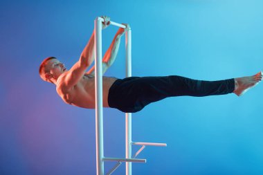 Yatay barda antrenman yapan, çıplak ayaklı ve üstsüz poz veren, siyah pantolon giyen, kavşakta spor yapan yakışıklı sporcu..