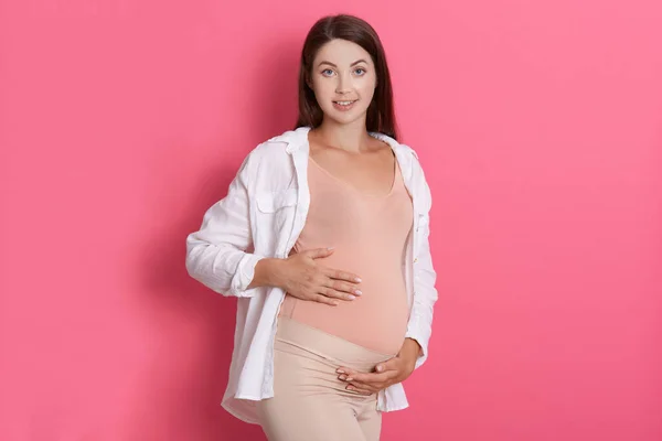 Hermosa Mujer Embarazada Abrazando Barriga Mirando Cámara Con Calma Expresión — Foto de Stock