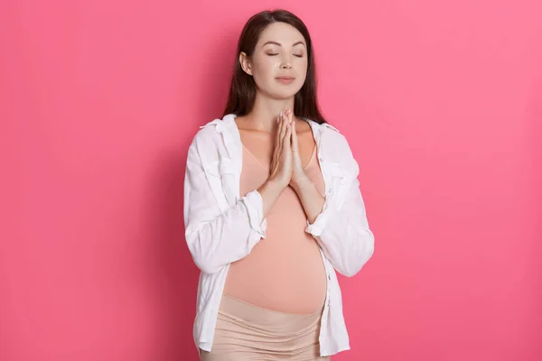 Piękna Kobieta Ciąży Medytuje Różowym Tle Trzyma Dłonie Razem Modli — Zdjęcie stockowe