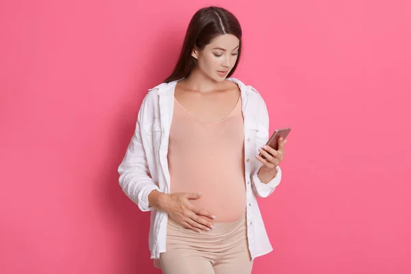 Mujer Embarazada Joven Con Pelo Oscuro Con Camisa Blanca Sostiene — Foto de Stock