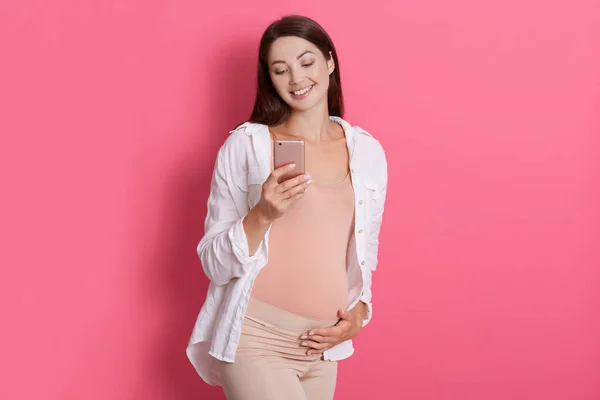Cheerful Expectant Mother Using Mobile Phone Chatting Her Husband Touching — Stock Photo, Image