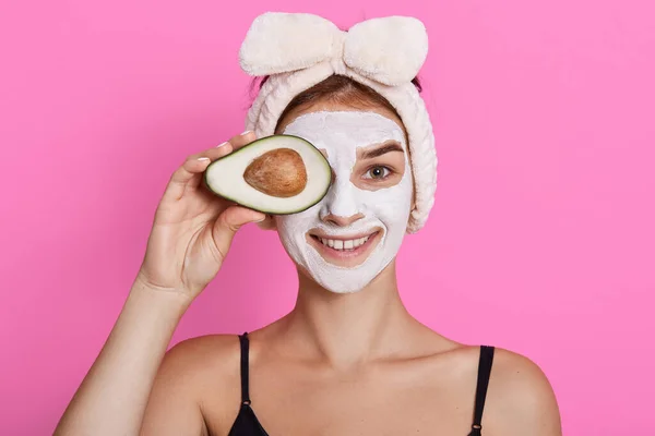 Jonge Vrouw Met Glimlach Houdt Avocado Tegen Haar Ogen Kijkt — Stockfoto