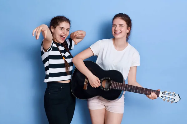 재미있는 소녀가 배경에 노래하고 기타를 연주하면서 자매들은 평상복을 집에서 재미있는 — 스톡 사진
