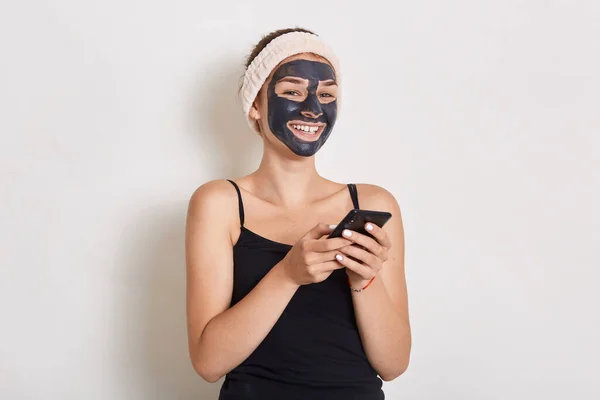 Vrouw Krijgt Zwart Gezichtsmasker Houdt Kleine Spiegel Handen Draagt Haarband — Stockfoto