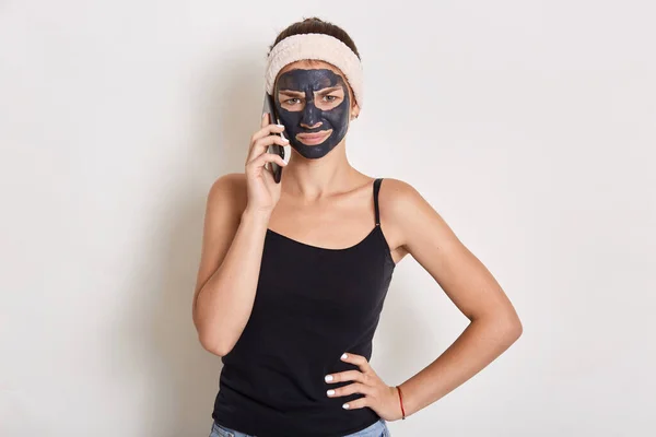 마스크를 소녀가 전화를 배경에 고립되어 헤드폰과 티셔츠를 엉덩이에 카메라를 봅니다 — 스톡 사진