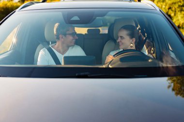Mutlu çift arabada oturuyor, gülümsüyor ve birbirlerine bakıyor güneşli bir günde birlikte yol yolculuğunun keyfini çıkarıyorlar..