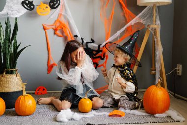 Cadılar Bayramı 'nda, biri gözlerini kapayan, diğeri de tuhaf dekorasyonlarla çevrili bir şekilde gülen iki genç kız kardeşin samimi bir fotoğrafı..