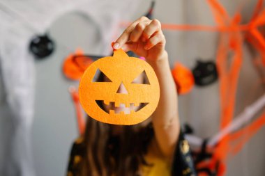 Kutlama, elinde parlak turuncu bir balkabağı kesimi tutan neşeli bir katılımcıyla başlıyor. Ürkütücü dekorasyonlar ve canlı renklerle çevrili..