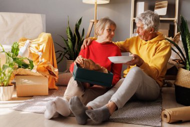 Yaşlılar sıcak bir öğleden sonra etrafı bitkiler ve rahat bir dekorla çevrili bir yemeği paylaşırken evde dinlenirler..