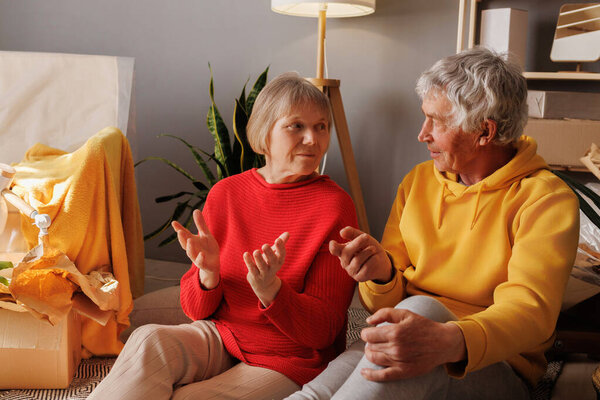 A senior couple sits comfortably in their cozy living room, engaged in a lively and heartfelt conversation, creating a warm atmosphere.