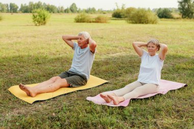 Huzurlu bir alanda, yaşlı bir çift ısınma egzersizleri yapar, sıcak güneş ışığının ve temiz havanın tadını çıkarırken aynı zamanda spor ve birliği teşvik eder..