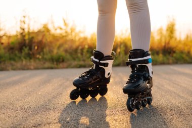 Parlak patenler, güneş batarken pürüzsüz bir yolda süzülür. Huzurlu park manzarası boyunca sıcak bir ışık yayar..