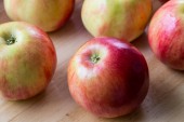 Červená jablka na hnědé dřevěné pozadí, přirozené potravy.
