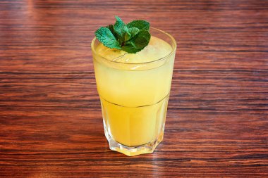 Nane ile taze limonata cam tahta masada bırakır. Doğal ışık