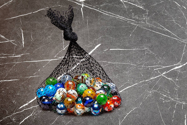 Bag of Multicolored marbles on textured marble table
