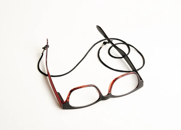 Stylové červené oční brýle s černým kabelem na bílém pozadí — Stock fotografie