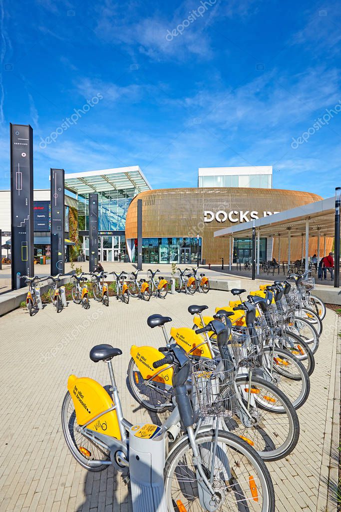 BRUSSELS, BELGIUM, 19 APRIL 2018: Stock of rental bike and some people resting at the Docks Bruxsel Main Entrance - New shopping district, in an area in full economic redeployment, a new quarter is hatching at schaerbeek, Brussels,Belgium