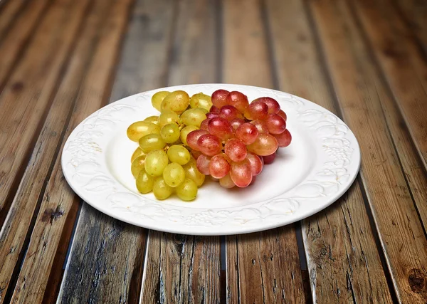 Two sorts of grapes, freshly washed on an old plate — Stock Photo, Image