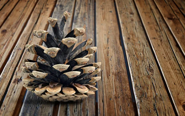 Otwarty stożek sosnowy na teksturowanym drewnianym stole — Zdjęcie stockowe