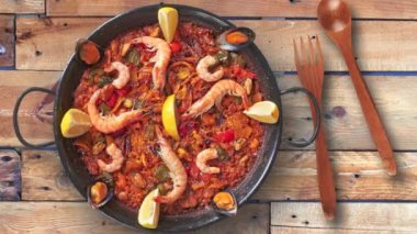 Pan of spanish paella on textured wooden table, view from above