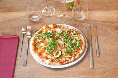 Kahverengi ahşap masa ve yuvarlak pizza ve mantarlı beyaz tabak.. 