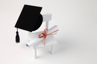 minyatür okul sandalye, beyaz zemin üzerine diploma kaydırma ve harç Pansiyon