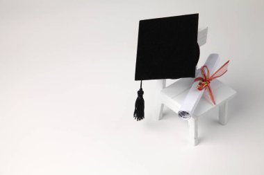 minyatür okul sandalye, beyaz zemin üzerine diploma kaydırma ve harç Pansiyon