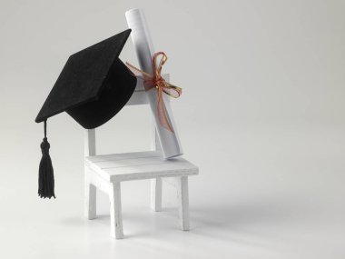 minyatür okul sandalye, beyaz zemin üzerine diploma kaydırma ve harç Pansiyon