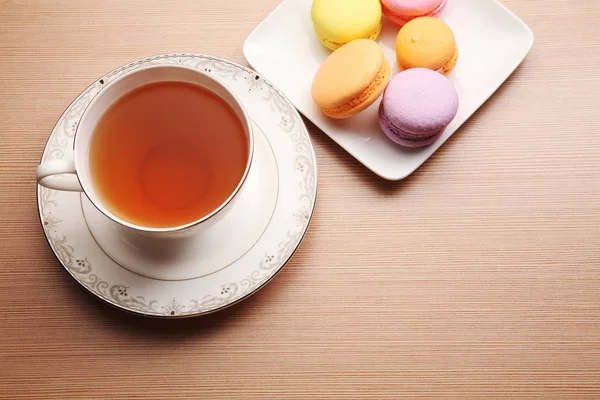 木桌上的茶杯和五颜六色的马卡龙 — 图库照片