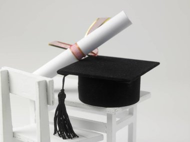 minyatür okul masa, sandalye, beyaz zemin üzerine diploma kaydırma ve harç kurulu