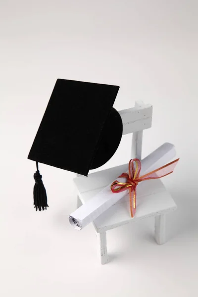 Miniatur Schulstuhl Diplom Schriftrolle Und Mörteltafel Auf Weißem Hintergrund — Stockfoto