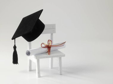 minyatür okul sandalye, beyaz zemin üzerine diploma kaydırma ve harç Pansiyon