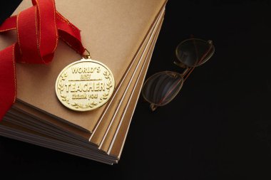 Öğretmenler günü tebrik kartı notebooklar, gözlük ve siyah arka plan üzerine altın madalya