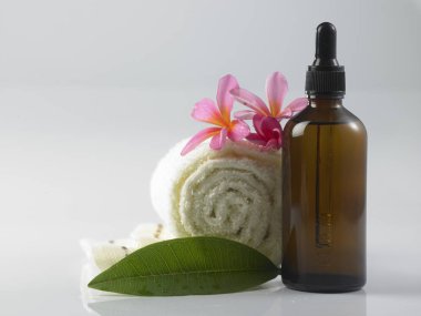 Masaj yağı ile havlu ve beyaz arka plan üzerinde pembe çiçek
