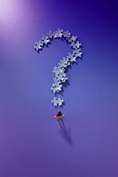 puzzle pieces and figurine form a question mark on the blue background