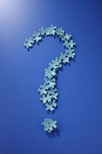 puzzle pieces form a question mark on the blue background